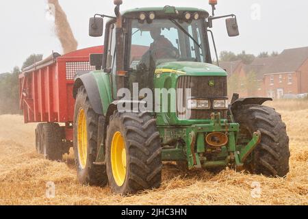 Ein Claas Lexion 440 Mähdrescher, der einen John Deere 6920s Traktor mit Gerste beladen wird Stockfoto