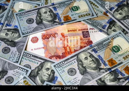 Russischer Rubel im Vergleich zum US-Dollar, Rubel-Banknote zwischen Dollarscheinen. Konzept der Sanktionen, starke Währung, Konfrontation, Wirtschaft Russlands und der USA Stockfoto