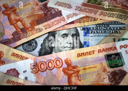 Russisches Rubel-Geld vs. US-Dollar, Franklin von 100-Dollar-Schein Uhren durch Rubel Banknotenstapel. Konzept von USD, Sanktionen, Währung, Konfrontation Stockfoto