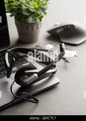 Arbeitsplatz, Home Office. Viele Objekte. Der Laptop verfügt über moderne Kopfhörer, eine Maus und eine Topfblume. Radio, Journalismus, Blogging, Präsentationen, vi Stockfoto