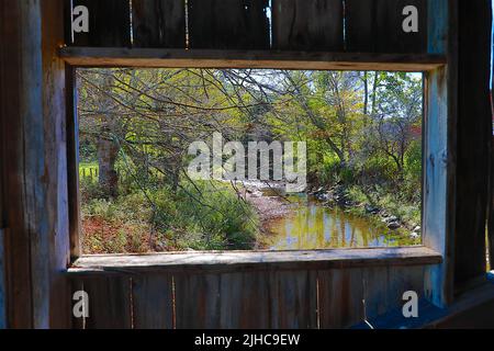 Szenen aus Grafton, Vermont, durch das Fenster einer überdachten Brücke machen diesen wunderschönen Ort landschaftlich und historisch, wenn der Bach unten vorbeifließt Stockfoto