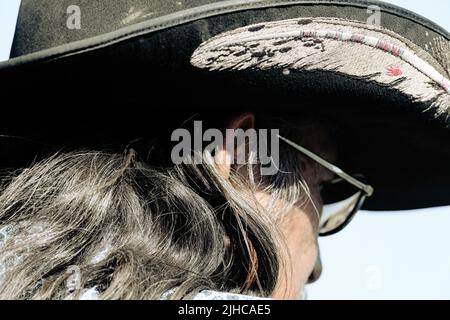 Ein Nahaufnahme-Foto eines Indianers mit indianischer Ureinwohner, der einen Cowboyhut trägt, der mit einer Feder bestickt ist Stockfoto