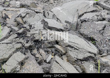 Ein Haufen verblassten, gebrochenen Asphalts, der von einer Straße entfernt wurde, damit er wieder gepflastert werden konnte. Konzentrieren Sie sich auf eine engere Asphaltdecke. Stockfoto