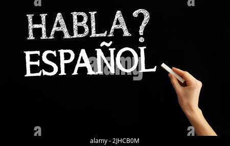 Handschriftentext HABLA ESPANOL? (SPRECHEN SIE SPANISCH?) Auf schwarzem Hintergrund Stockfoto