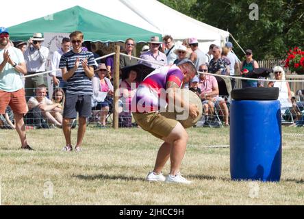 Einem Teilnehmer gelingt es, ein schweres Gewicht im Rahmen der Performance von Adrian Smith, bekannt als Mighty Smith, einem der stärksten Männer Großbritanniens, zu heben. Stockfoto