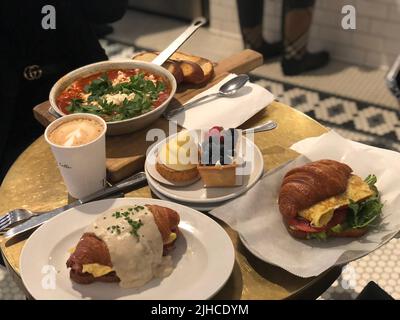 Eine Nahaufnahme von Croissant-Sandwiches, Dessert und Suppe auf einem Holztisch Stockfoto