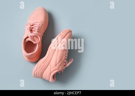 Paar neue rosa Damen Sneakers oder Sportschuhe auf blauem Hintergrund. Blick von oben. Flach liegend. Stockfoto