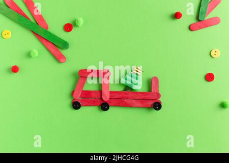 Rotes Auto mit Tannenbaum aus Holzstäben. Handgefertigt. Projekt der Kreativität der Kinder, Kunsthandwerk, Kunsthandwerk für Kinder. Stockfoto
