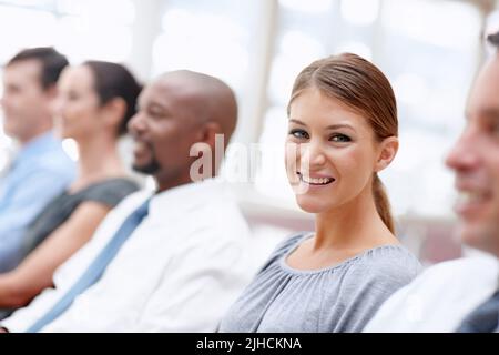 Engagiert sich für das Geschäft. Ein schöner Geschäftsbeauftragter lächelt Sie an, während Sie an einem Meeting teilnehmen. Stockfoto