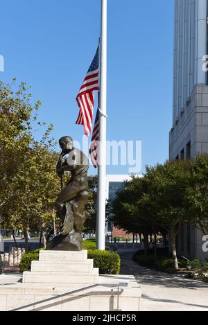 SANTA ANA, KALIFORNIEN - 23. SEPTEMBER 2020: Statue mit Flagge am Half Mast im Ronald Reagan Courthouse und Federal Building. Stockfoto