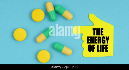 Medizin und Gesundheitskonzept. Auf einem blauen Hintergrund befinden sich Pillen und ein Handaufkleber mit der Aufschrift - die Energie des Lebens Stockfoto