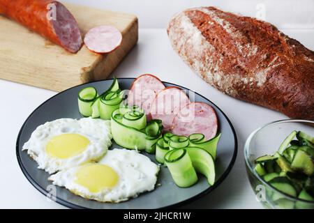 Zastrak-Eier Rühreier Wurst Salat Gurken auf der Trael Blick von der Seite oben. Traditionelles englisches amerikanisches Frühstück. Erste Mahlzeit. Das Benef Stockfoto