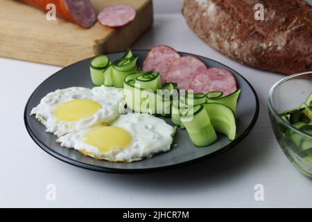 Zastrak-Eier Rühreier Wurst Salat Gurken auf der Trael Blick von der Seite oben. Traditionelles englisches amerikanisches Frühstück. Erste Mahlzeit. Das Benef Stockfoto