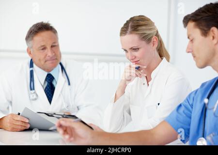 Um Rat zu den einzelnen Gebühren zu bitten. Drei medizinische Fachkräfte treffen sich gemeinsam. Stockfoto