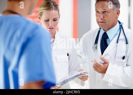 Wir müssen die Medikamente aufbringen. Drei Ärzte, die eine ernsthafte Diskussion über einen Patienten führen. Stockfoto