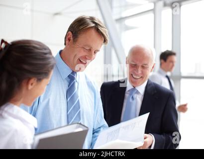 Diese Zahlen sehen toll aus. Lächelnde Geschäftsleute, die in einem informellen Gespräch gemeinsam Dokumente durchgehen. Stockfoto