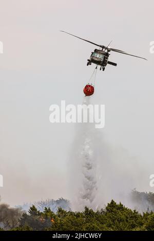 Eine Oklahoma Army National Guard UH-60 Black Hawk lässt beim Brand 702 in Blaine County, Oklahoma, 16. Juli 2022 mehr als 600 Gallonen Wasser fallen. Die Oklahoma National Guard unterstützt die Oklahoma Forestry Services und lokale Feuerwehren bekämpfen den Brand von oben mit einem UH-60 Black Hawk und LUH-72 Lakota. (Foto der Oklahoma National Guard von Sgt. Anthony Jones) Stockfoto