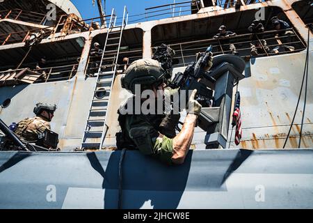 Ein schwedisches Marine-Regiment mit 4. Marine-Regiment, schwedisches Amphibienkorps bietet Sicherheit während eines Angriffs von einem Kampfschiff mit Special Boat Team – TWELVE, U.S. Naval Special Warfare Group FOUR während der Übung TYR 22 im NATO Maritime Interdiction Operational Training Center (NMIOTC) in Souda Bay, Griechenland, 13. Juli 2022. TYR 22 ist eine maritime Interdiktionsübung, die bei NMIOTC durchgeführt wird und die schwedische Marine, US-Marine und Kampfkommandantinnen der US-Marine zusammenbringt, um die operativen Kapazitäten, Fähigkeiten und Interoperabilität der US- und NATO-Partner zu verbessern. (USA Stockfoto