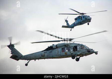 PEARL HARBOR (14. Juli 2022) MH-60s Sea Hawk-Hubschrauber nähern sich einer Hubschrauberlandezone (HLZ), um während des Rim of the Pacific (RIMPAC) 2022 auf Ford Island, Hawaii, 14. Juli 2022, bedeutende Besucher abzuholen. 26 Nationen, 38 Schiffe, vier U-Boote, mehr als 170 Flugzeuge und 25.000 Mitarbeiter nehmen vom 29. Juni bis zum 4. August an RIMPAC in und um die Hawaii-Inseln und Südkalifornien Teil. RIMPAC, die weltweit größte internationale maritime Übung, bietet eine einzigartige Ausbildungsmöglichkeit und fördert und pflegt kooperative Beziehungen zwischen den Teilnehmern, die für wichtig sind Stockfoto