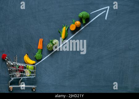 Gemüse und Obst und Pfeile nach oben auf Kreidetafel Hintergrund.Lebensmittelpreise.Gemüse und Obst Preiserhöhung. Stockfoto