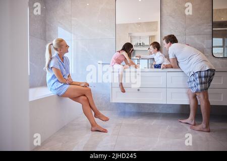 Glückliche Familie mit zwei Kindern, die sich Zähne putzen. Das junge kaukasische Paar lehrte ihre Kinder, gute Mundhygiene zu üben. Setzen Sie ein gutes Beispiel durch Stockfoto