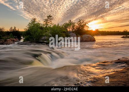 Bei den Burleigh Falls, Ontario, stürzt das Wasser über die Granitfelsen, mit einem wunderschönen Sternenhimmel über dem Stoney Lake in der Ferne. Stockfoto