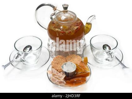 Teetasse aus Glas mit Tassen und kristallisierten Früchten auf weißem Hintergrund Stockfoto