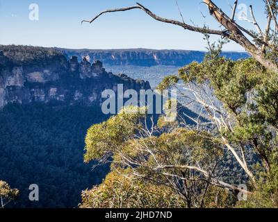 Die drei Schwestern und das Jamison Valley an einem sonnigen Wintermorgen mit der Sandsteinwand des Königstableland im Hintergrund, Katoomba, Blue Mountains Stockfoto