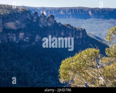 Die drei Schwestern und das Jamison Valley an einem sonnigen Wintermorgen mit der Sandsteinwand des Königstableland im Hintergrund, Katoomba, Blue Mountains Stockfoto