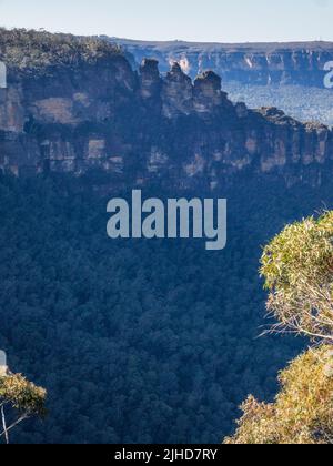 Die drei Schwestern und das Jamison Valley an einem sonnigen Wintermorgen mit der Sandsteinwand des Königstableland im Hintergrund, Katoomba, Blue Mountains Stockfoto