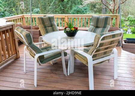 Issaquah, Washington, USA. Metall-Terrassenstühle und -Tisch auf einer zusammengesetzten Terrasse mit Zederngeländer. Stockfoto