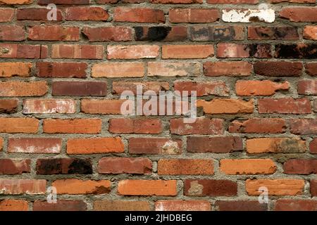 Nahaufnahme einer alten verwitterten roten Ziegelwand eines Gebäudes, das Mörtel zeigt Stockfoto