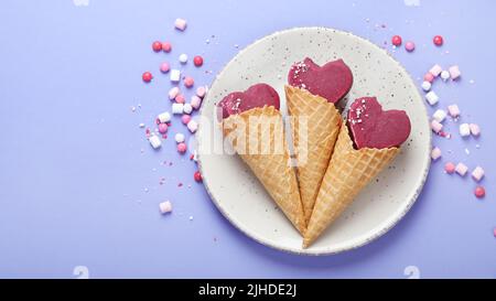 Violettes Heidelbeer-Eis auf lilafarbenem Hintergrund. Stimmungsvolles, süßes Menükonzept. Draufsicht, flach liegend, Kopierbereich Stockfoto