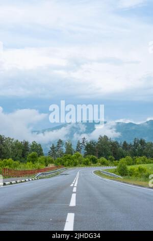 Leere Straße. Speedway ohne Autos in den Bergen inmitten von Pinienwäldern. Abenteuer- oder Roadtrip-Hintergrund. Stockfoto