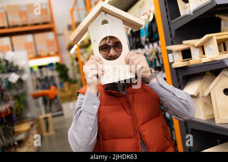 Kunde im Gartengeschäft, der sich mit Vogelhaus herumtollt Stockfoto