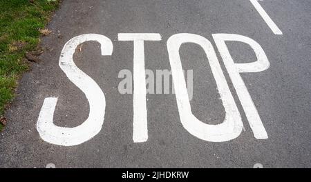 In einer Straße in Großbritannien weiß lackiertes Stoppschild. Stockfoto