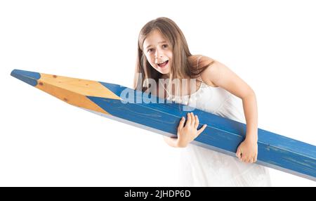 Ein niedliches kleines Mädchen hält mit großer Anstrengung einen riesigen blauen Bleistift in ihren Händen - isoliert auf Weiß. Stockfoto