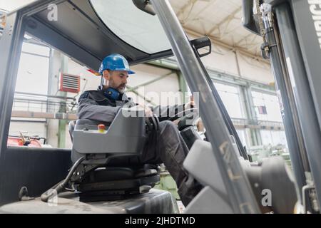 Glücklich reifen Mann Gabelstapler LKW Fahrer Hubpalette im Lagerhaus . Stockfoto