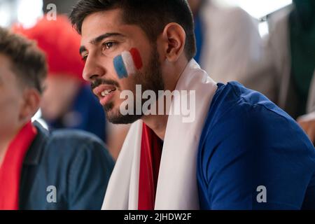 Beunruhigte Fußballfans, die die französische Nationalmannschaft bei einem Live-Fußballspiel im Stadion unterstützen. Stockfoto