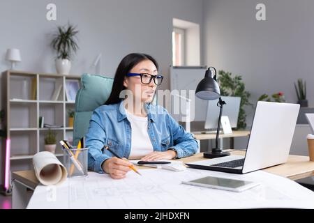 Junge schöne asiatische Frau Architektin Designer trägt Brille am Desktop-Computer arbeiten und Zeichnung mit Bleistift, arbeiten an Projekt. Stockfoto