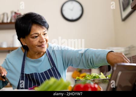 Aus der Perspektive einer lächelnden, reifen Frau mit kurzen Haaren, die in der Küche Lebensmittel kocht Stockfoto