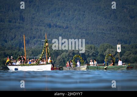 Radolfzell Am Bodensee, Deutschland. 18.. Juli 2022. Mit Blumenkränzen geschmückte Boote fahren während der Moos Wasserprozession über den Bodensee zum Ufer von Radolfzell. Die Prozession fand erstmals 1926 auf dem Wasser über den Bodensee statt. Es stammt aus dem 18.. Jahrhundert. 1796 wurden die Bürger von Moos von einer Viehpest verschont - aus Dankbarkeit dafür findet die Veranstaltung jedes Jahr am dritten Montag im Juli statt. Quelle: Felix Kästle/dpa/Alamy Live News Stockfoto