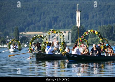 Radolfzell Am Bodensee, Deutschland. 18.. Juli 2022. Mit Blumenkränzen geschmückte Boote fahren während der Moos Wasserprozession über den Bodensee zum Ufer von Radolfzell. Die Prozession fand erstmals 1926 auf dem Wasser über den Bodensee statt. Es stammt aus dem 18.. Jahrhundert. 1796 wurden die Bürger von Moos von einer Viehpest verschont - aus Dankbarkeit dafür findet die Veranstaltung jedes Jahr am dritten Montag im Juli statt. Quelle: Felix Kästle/dpa/Alamy Live News Stockfoto