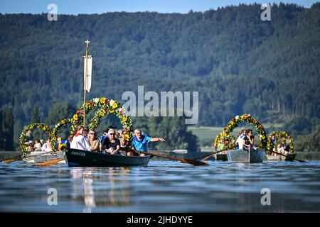 Radolfzell Am Bodensee, Deutschland. 18.. Juli 2022. Mit Blumenkränzen geschmückte Boote fahren während der Moos Wasserprozession über den Bodensee zum Ufer von Radolfzell. Die Prozession fand erstmals 1926 auf dem Wasser über den Bodensee statt. Es stammt aus dem 18.. Jahrhundert. 1796 wurden die Bürger von Moos von einer Viehpest verschont - aus Dankbarkeit dafür findet die Veranstaltung jedes Jahr am dritten Montag im Juli statt. Quelle: Felix Kästle/dpa/Alamy Live News Stockfoto