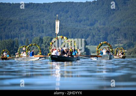 Radolfzell Am Bodensee, Deutschland. 18.. Juli 2022. Mit Blumenkränzen geschmückte Boote fahren während der Moos Wasserprozession über den Bodensee zum Ufer von Radolfzell. Die Prozession fand erstmals 1926 auf dem Wasser über den Bodensee statt. Es stammt aus dem 18.. Jahrhundert. 1796 wurden die Bürger von Moos von einer Viehpest verschont - aus Dankbarkeit dafür findet die Veranstaltung jedes Jahr am dritten Montag im Juli statt. Quelle: Felix Kästle/dpa/Alamy Live News Stockfoto