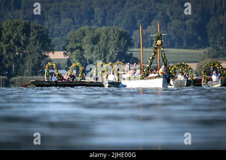 Radolfzell Am Bodensee, Deutschland. 18.. Juli 2022. Mit Blumenkränzen geschmückte Boote fahren während der Moos-Wasserprozession über den Bodensee zum Ufer von Radolfzell. Die Prozession fand erstmals 1926 auf dem Wasser über den Bodensee statt. Es stammt aus dem 18.. Jahrhundert. 1796 wurden die Bürger von Moos von einer Viehpest verschont - aus Dankbarkeit dafür findet die Veranstaltung jedes Jahr am dritten Montag im Juli statt. Quelle: Felix Kästle/dpa/Alamy Live News Stockfoto