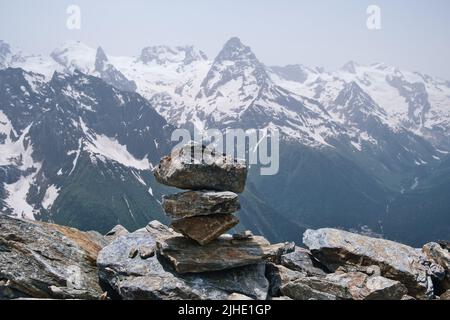 Steinhaufen auf dem Berg vor dem Hintergrund von Bergschneespitzen. Konzept von Gleichgewicht, Gleichgewicht und Harmonie. Stockfoto