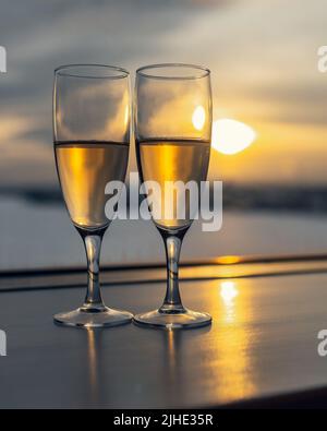 Zwei Gläser mit Champagner am Fenster bei Sonnenuntergang Stockfoto