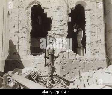 Ein Vintage-Foto vom 9. 1941. Dezember zeigt einen britischen Soldaten, der die Bombe betrachtend, beschädigte Ruinen einer katholischen Kirche nach der Belagerung von Tobruk, Libyen, Nordafrika während des Zweiten Weltkriegs Stockfoto