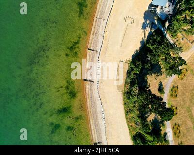 Eine Luftaufnahme eines sandigen Pfades zwischen Wiese und grünen Bäumen im Freien Stockfoto